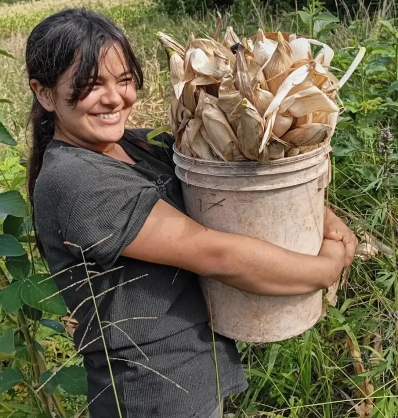 Jazmín Furlán cargando material orgánico en la chacra